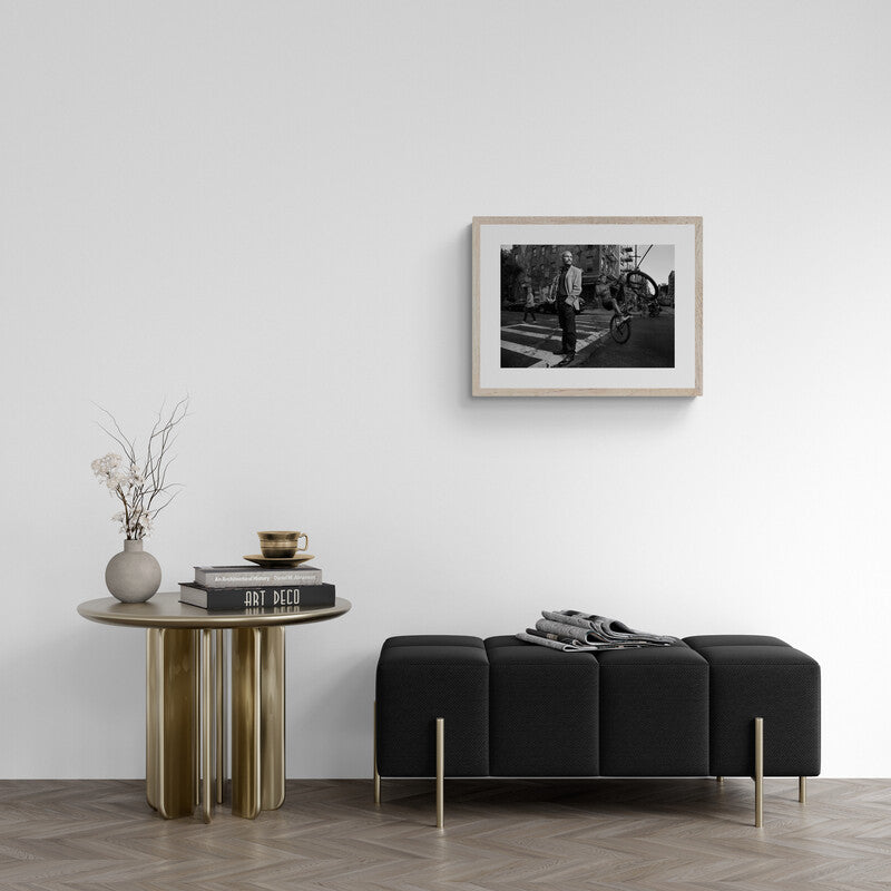 Modern living room with black sofa, wooden side table, and framed photo on wall.
