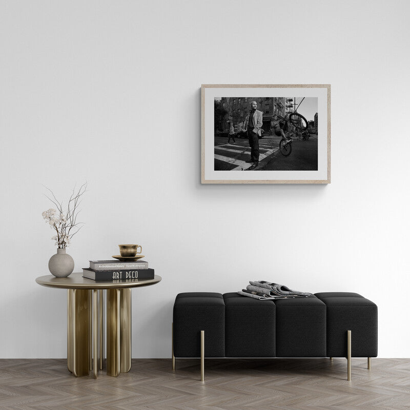 Modern interior with a black sofa, wooden side table, and framed photograph on the wall.