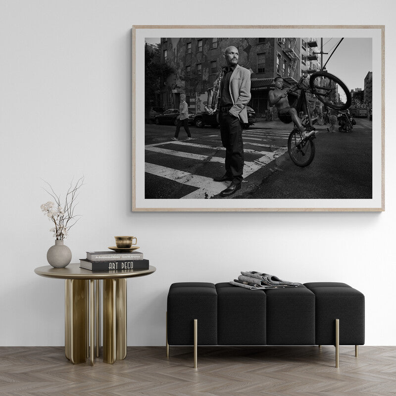 Framed black and white photograph of a man on a city street above a modern living room setup.