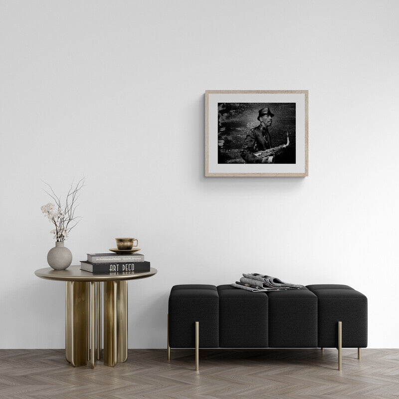 Modern living room with a black sofa, wooden side table, and framed artwork on the wall.