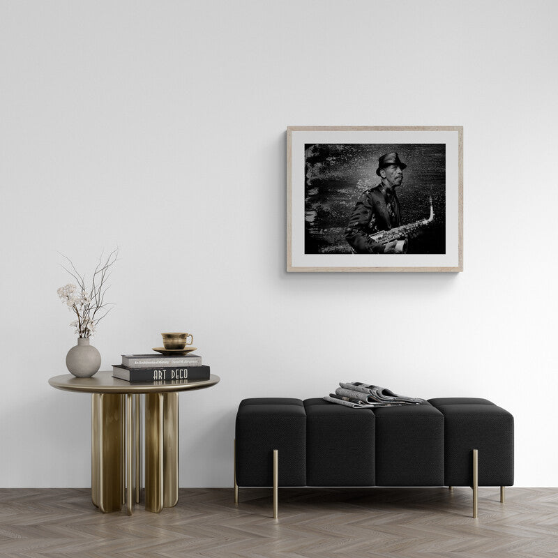 Modern living room with a black sofa, wooden side table, and framed picture on the wall.