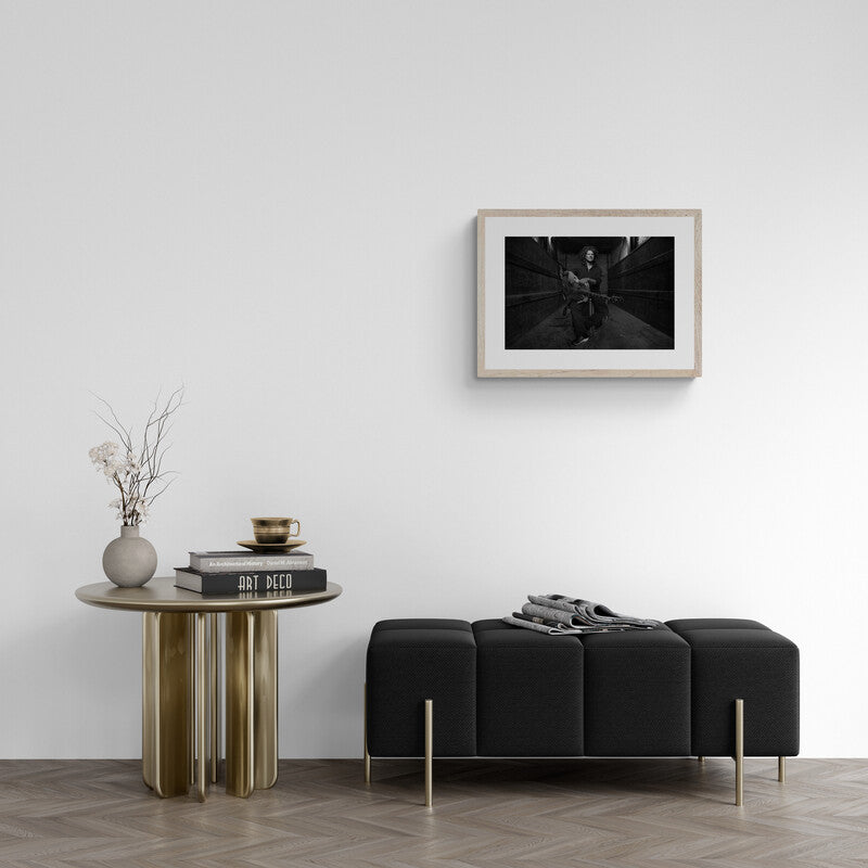 Modern living room with a black sofa, wooden side table, and framed artwork on the wall.