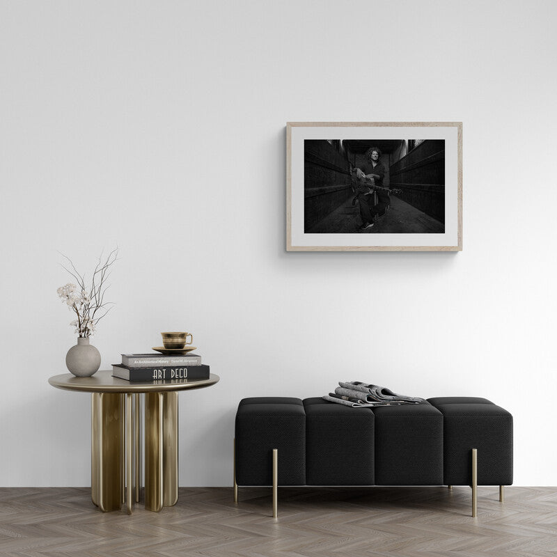 Modern living room with a black sofa, wooden side table, and framed artwork on the wall.