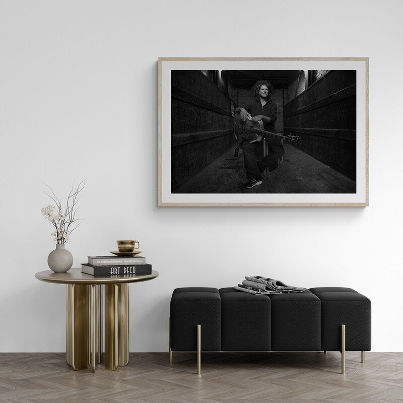 Framed black and white artwork on a wall above a modern black sofa and side table.
