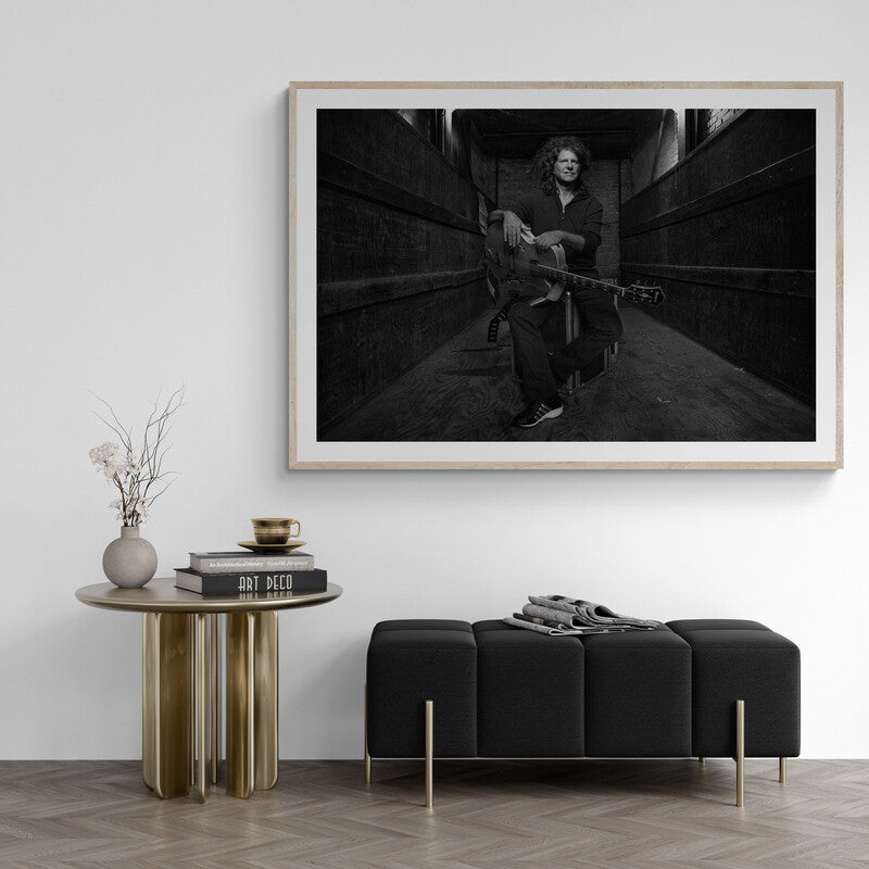 Framed black and white artwork of a person sitting on a staircase in a modern living room.