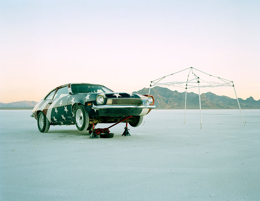 Vintage car on a salt flat with a tent in the background
