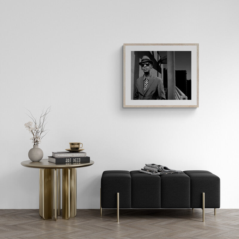 Modern living room with a black sofa, wooden side table, and framed portrait on the wall.