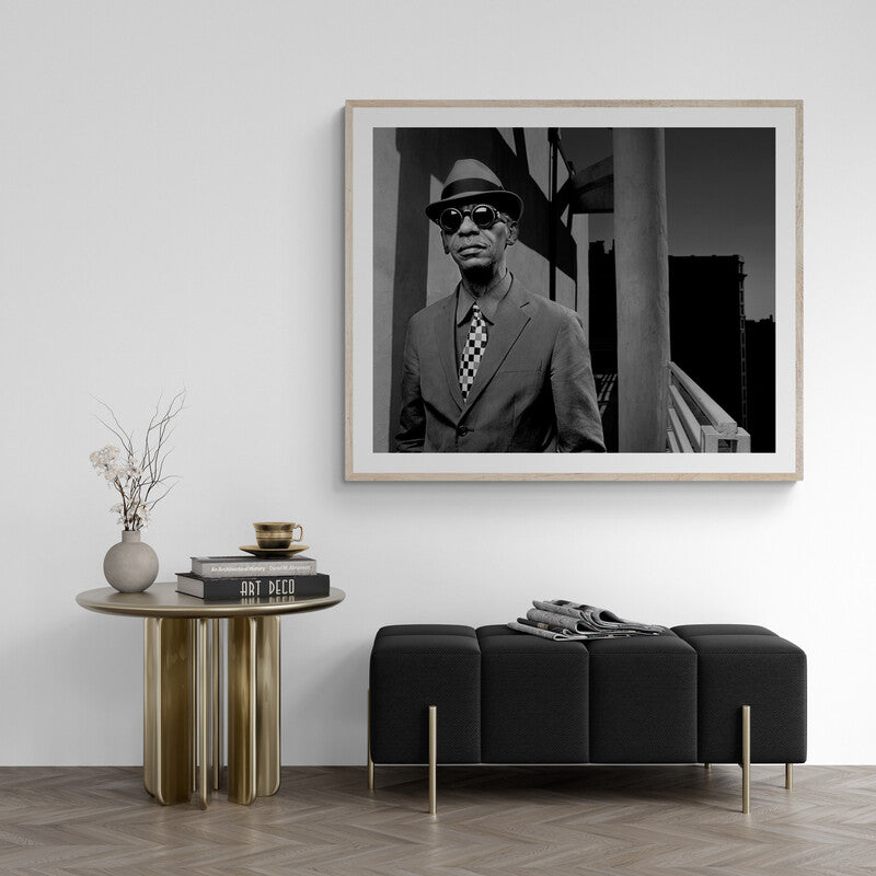 Framed black and white portrait of a man in a suit and hat above a modern living room setup.