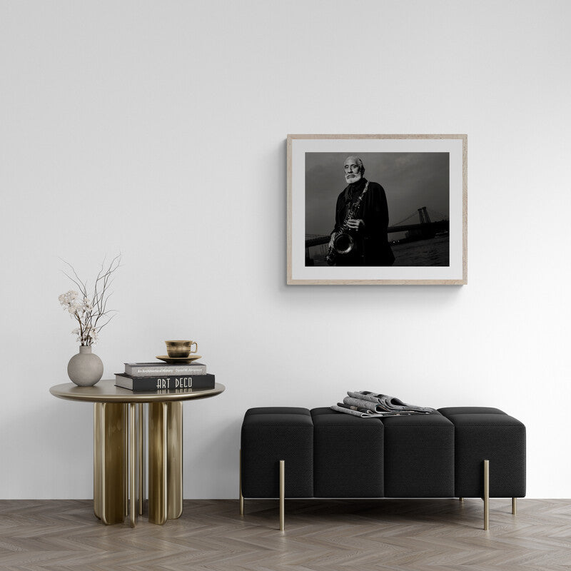 Modern living room with a black sofa, wooden side table, and framed portrait on the wall.