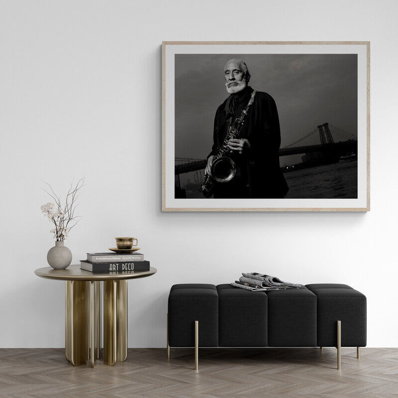 Framed black and white portrait of a man playing a saxophone above a modern living room setup.