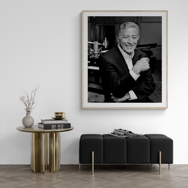 Framed black and white portrait of a man in a stylish room with a table and bench.