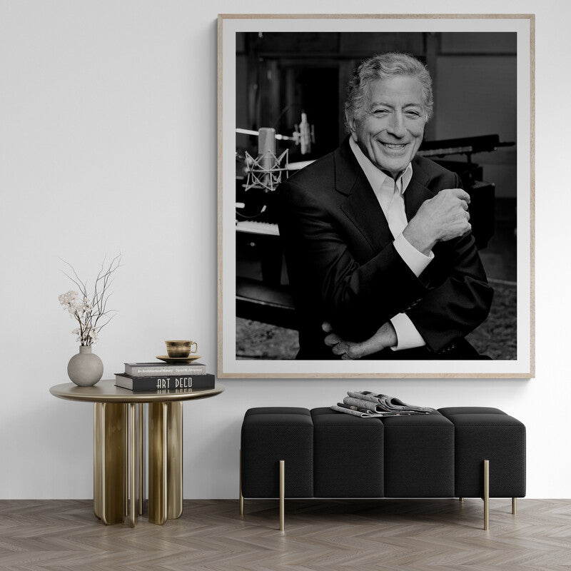 Framed black and white portrait of a man in a stylish interior setting with a table and bench.