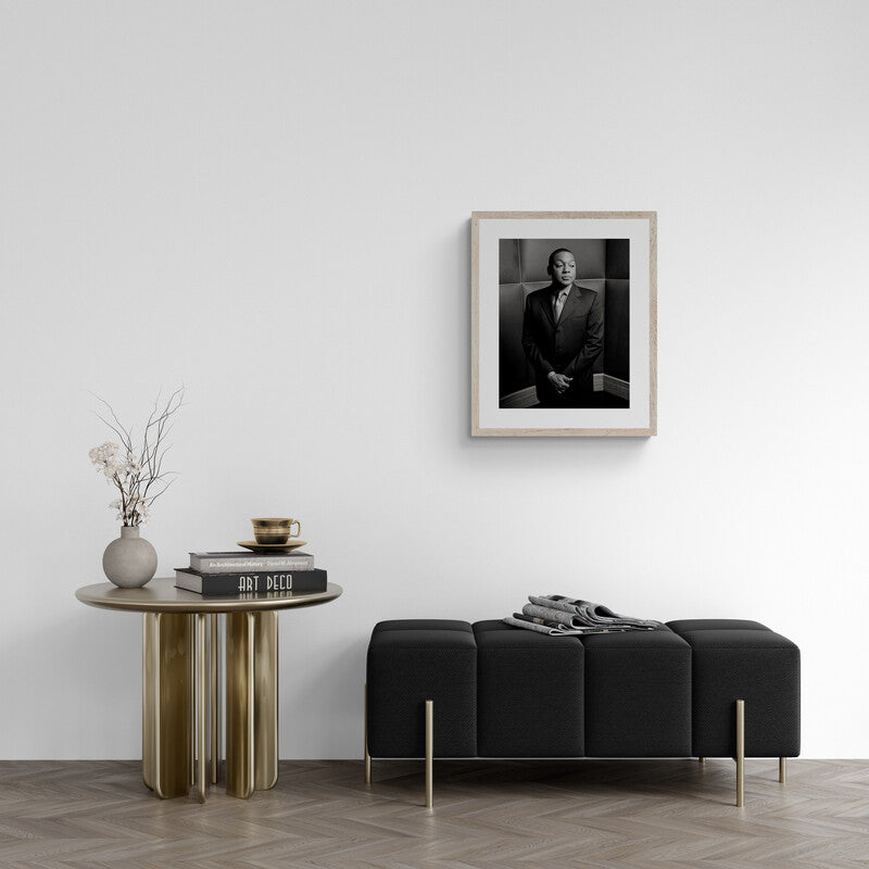 Modern interior with a black sofa, wooden side table, and framed portrait on the wall.