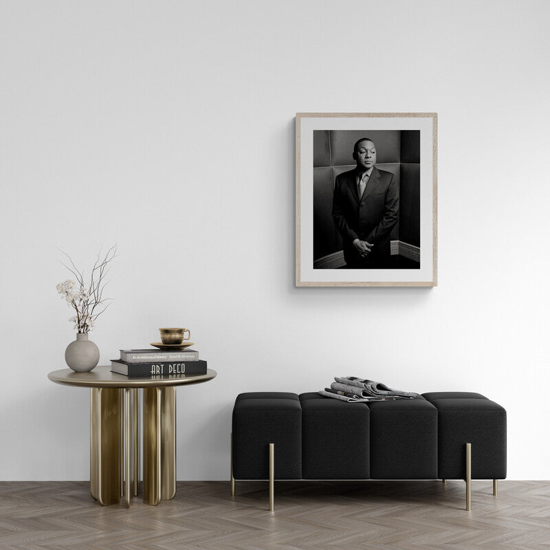 Modern interior with a black sofa, wooden side table, and framed portrait on the wall.