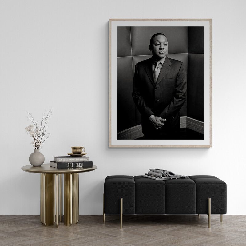 Framed black and white portrait of a man in a suit on a wall above a modern black sofa and side table.