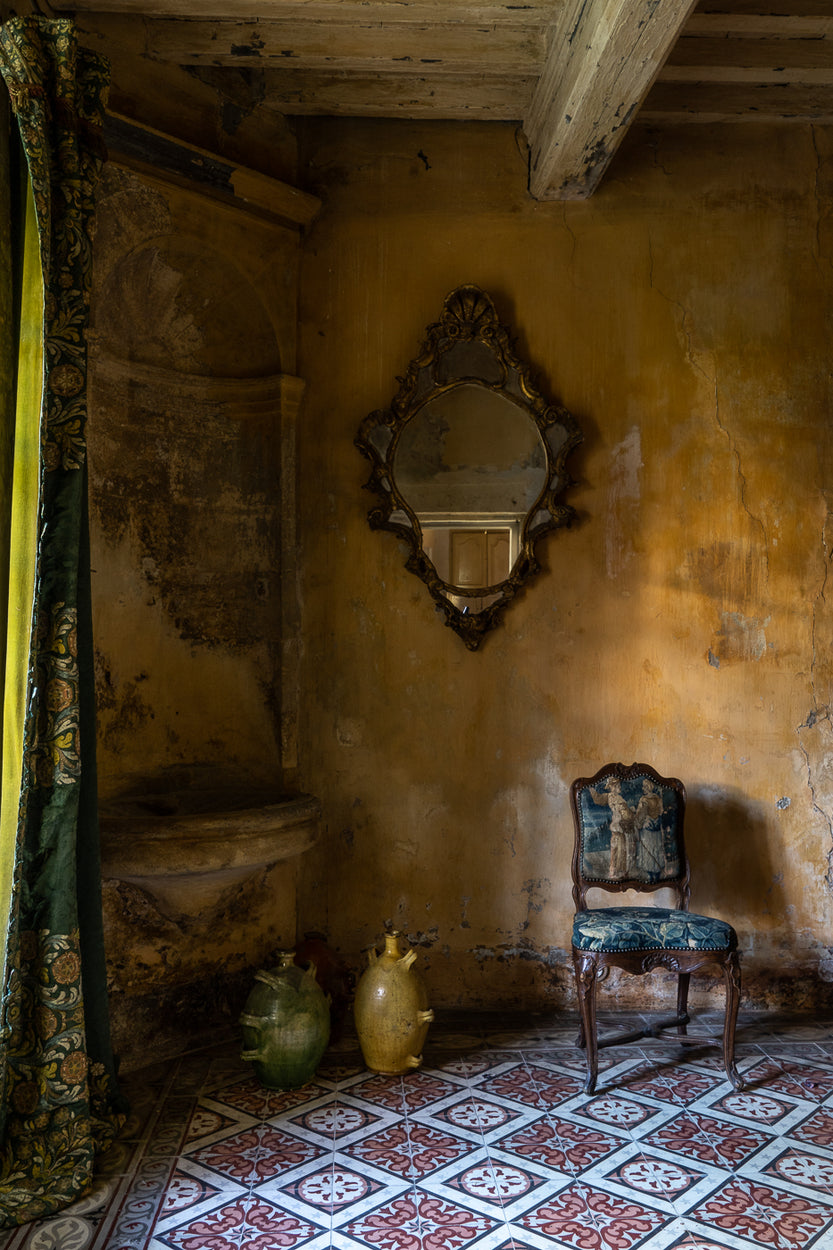 Vintage room with a mirror and chair on a patterned floor.