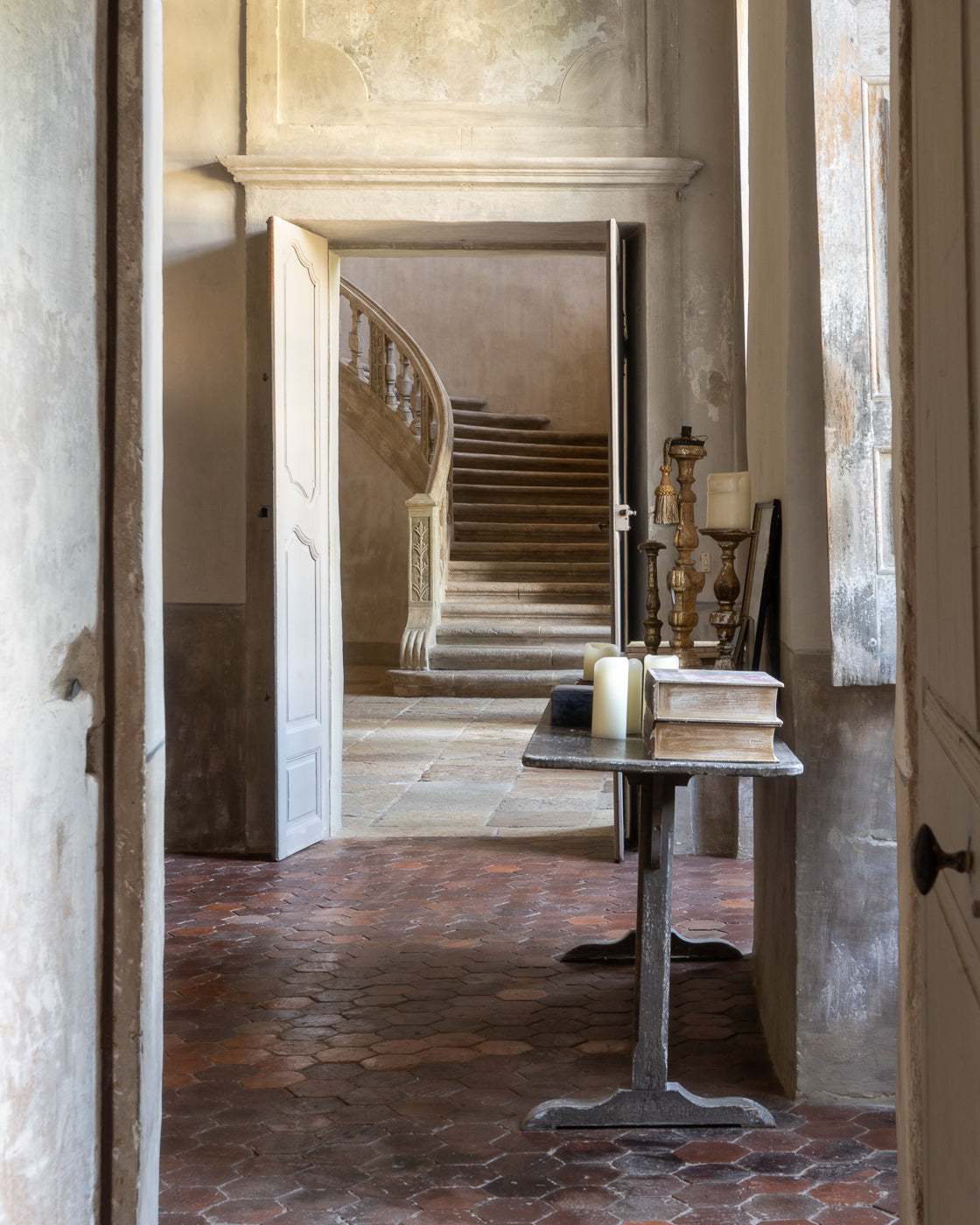Staircase in an old French castle with a table and candles in the foreground.