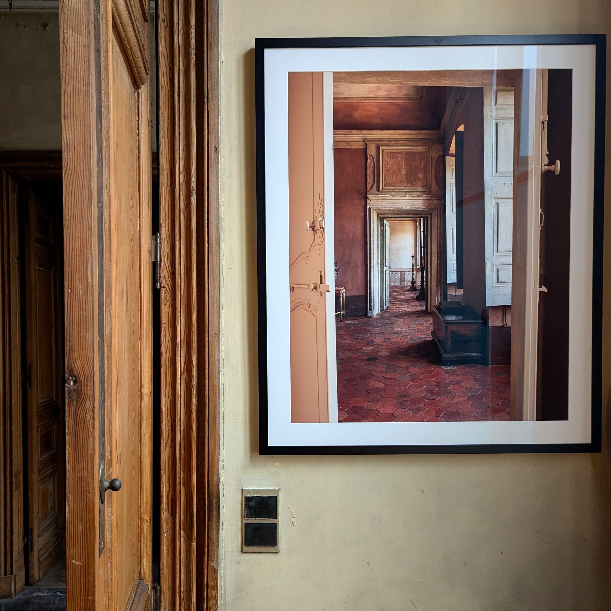 Framed photograph of a hallway on a wall next to a door.