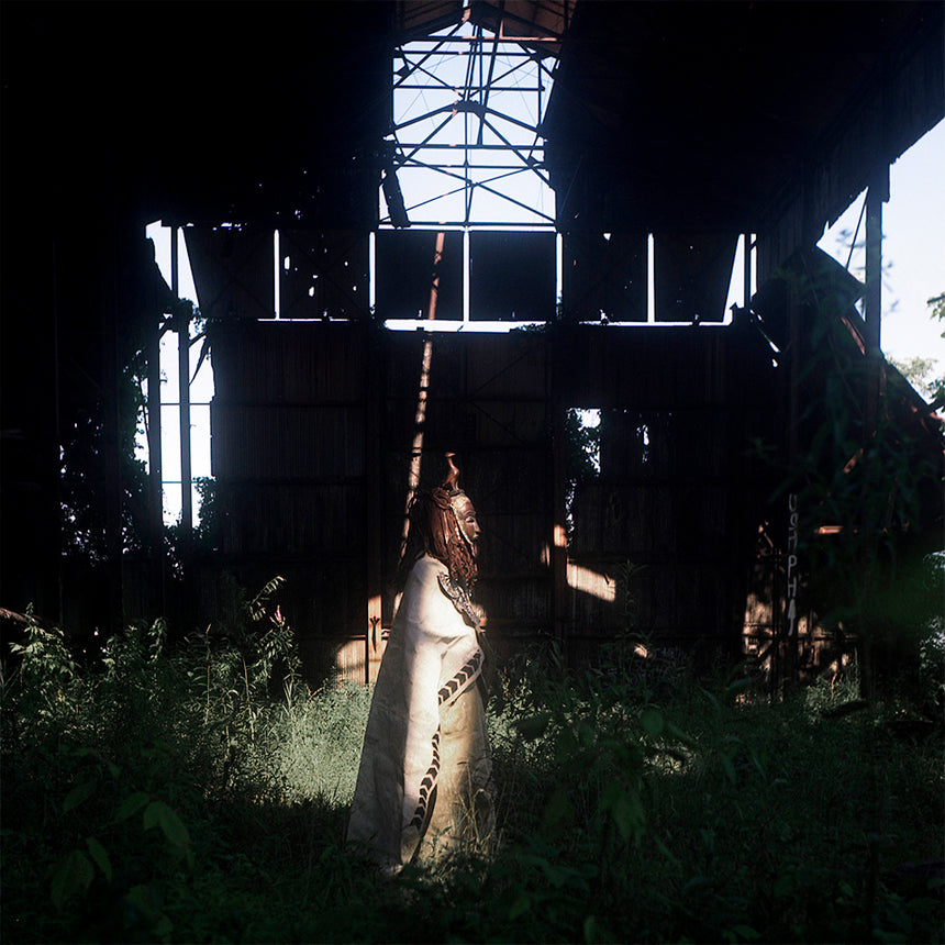 Person in a white dress standing in a dark, overgrown industrial setting