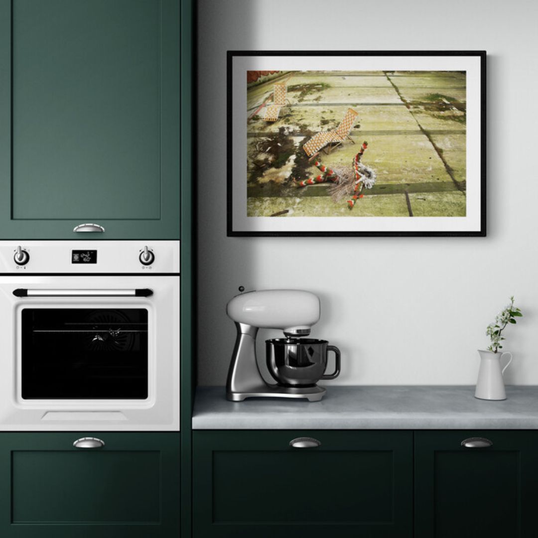 Kitchen interior with green cabinets, white appliances, and a framed picture on the wall.
