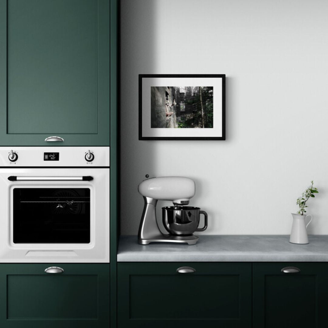 Modern kitchen with green cabinets, white appliances, and a framed picture on the wall.