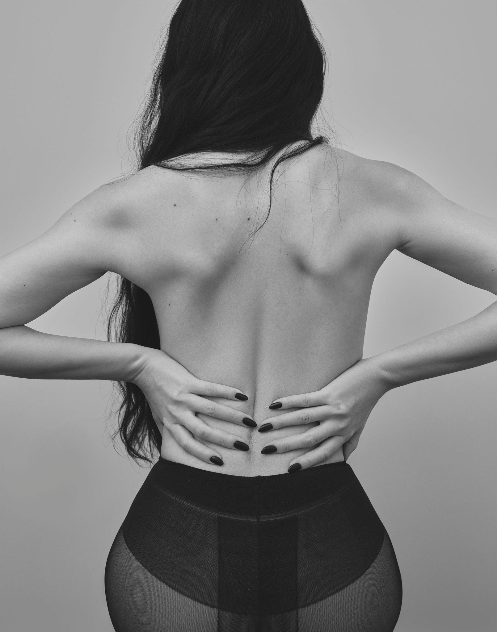 Black and white image of a person with their back to the camera, showing a visible spine.