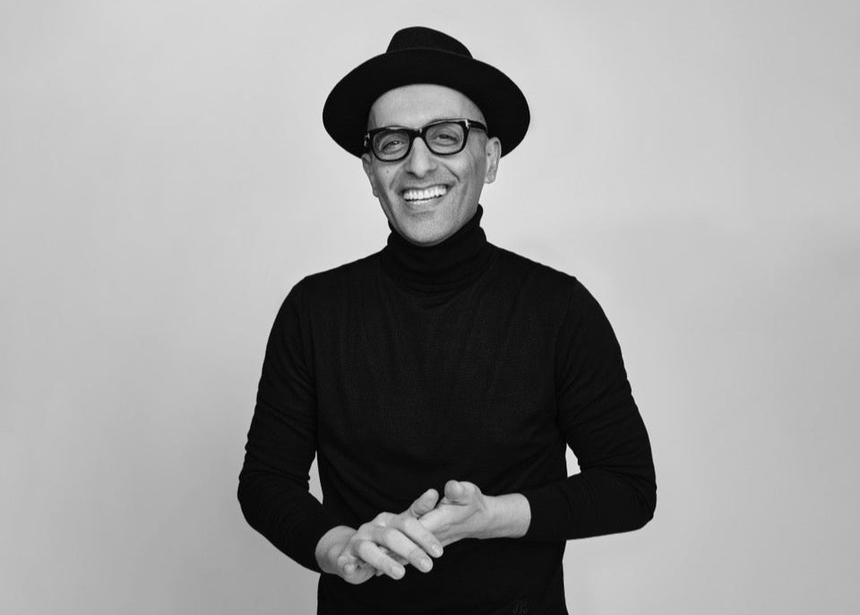 Black and white photo of a person wearing a black turtleneck and hat, smiling.