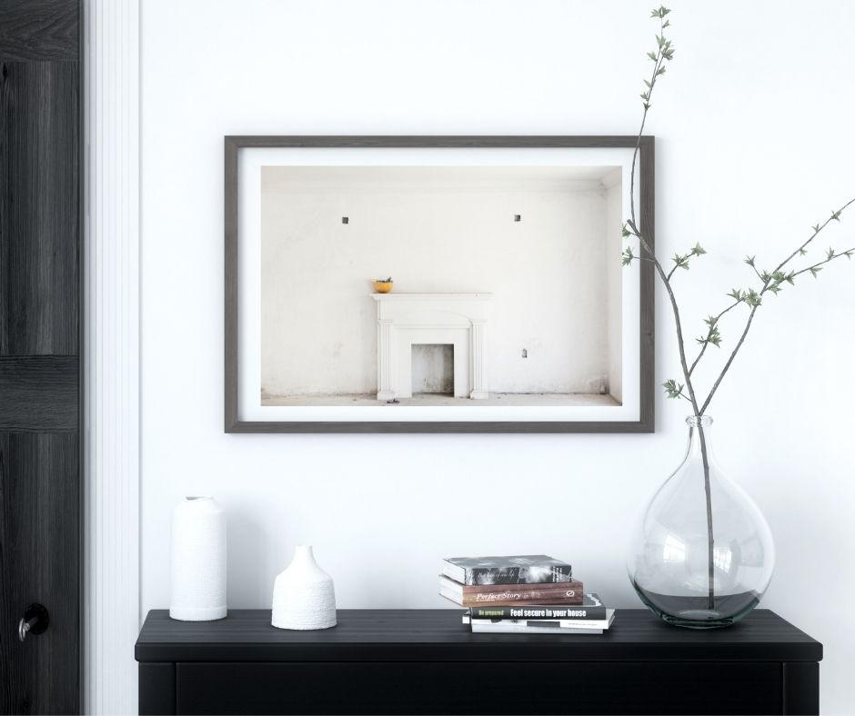 Framed artwork on a wall above a black console table with decorative items.