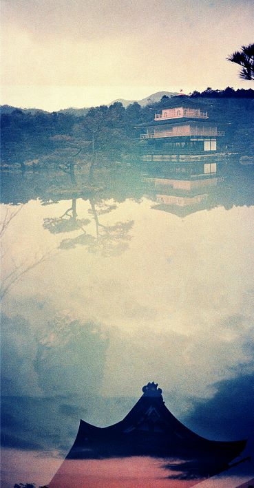 Traditional Japanese temple reflected in water with mountains in the background