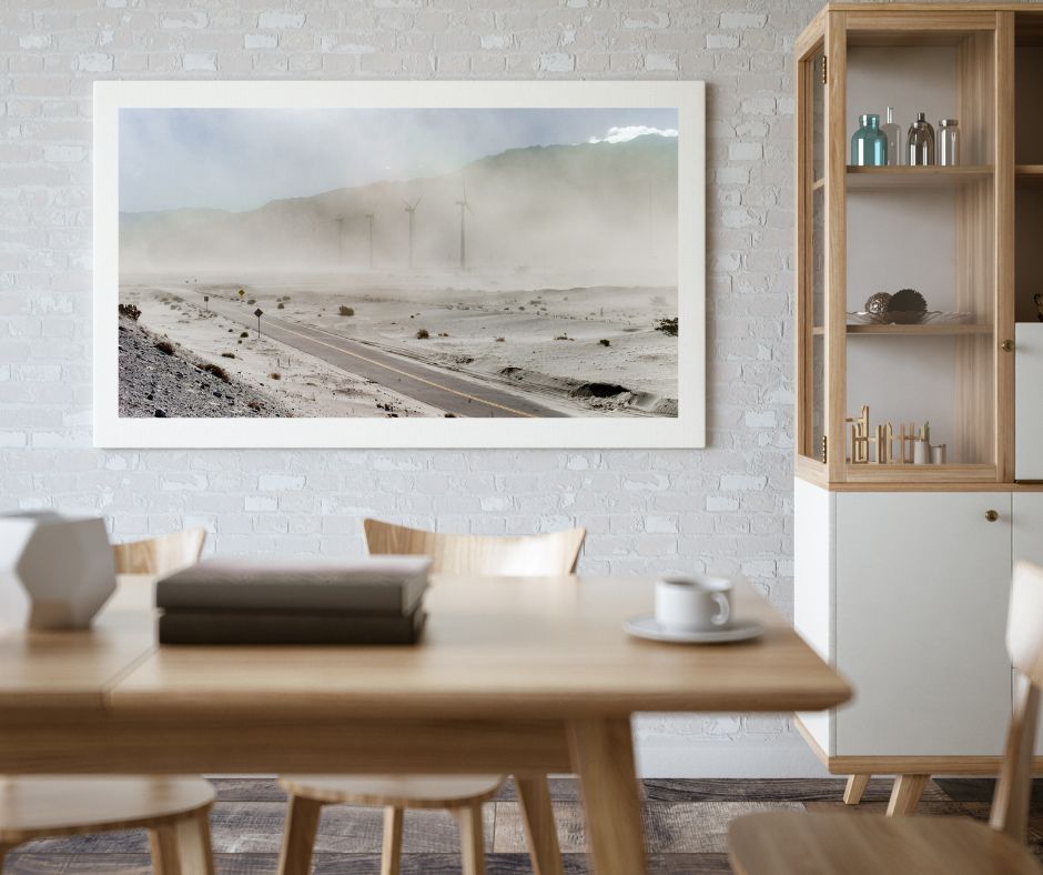 Dining room with a framed landscape print on the wall, wooden table, and chairs.