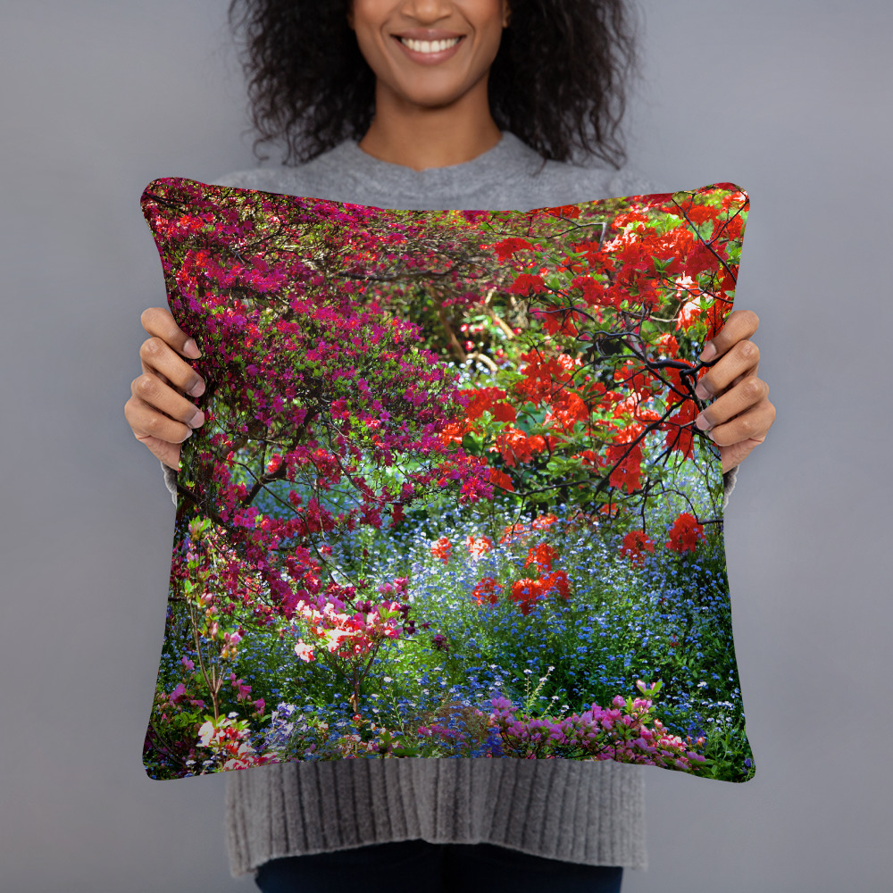 Woman holding a Square pillow with the photograph of a shaded and flowery spot in a park