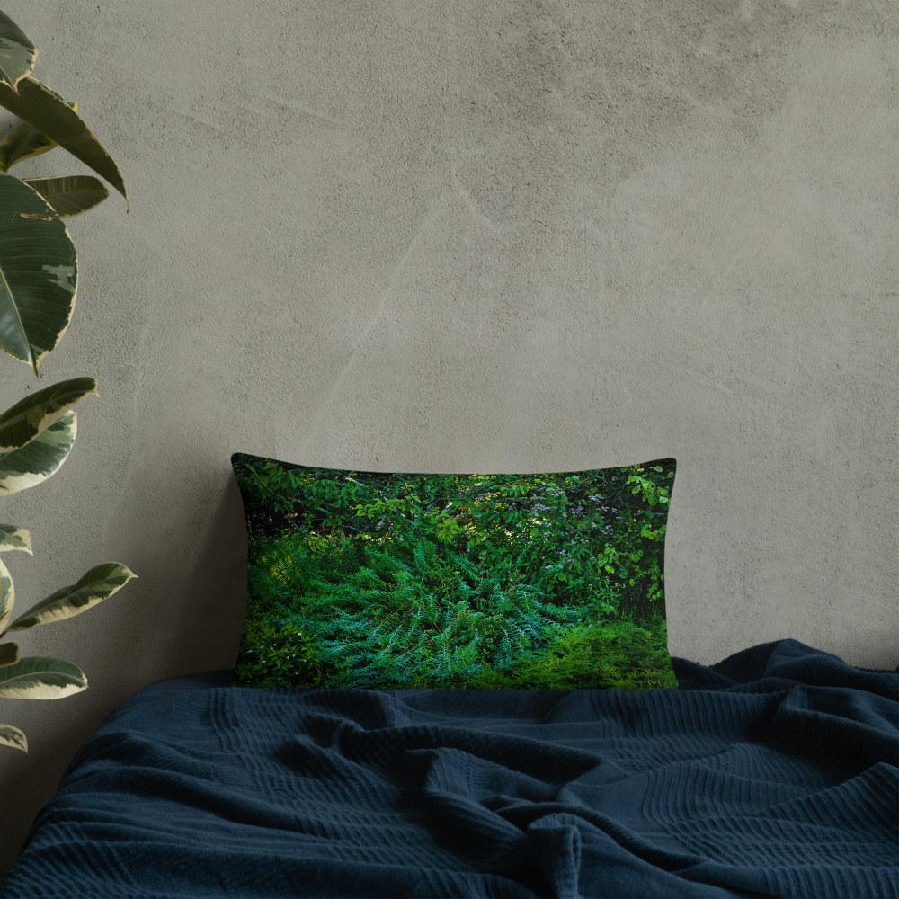 Rectangular pillow with a photograph of lush greenery leaned against a wall