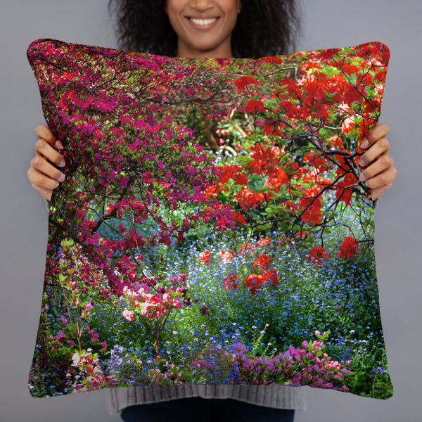 Woman holding a Square pillow with the photograph of a shaded and flowery spot in a park