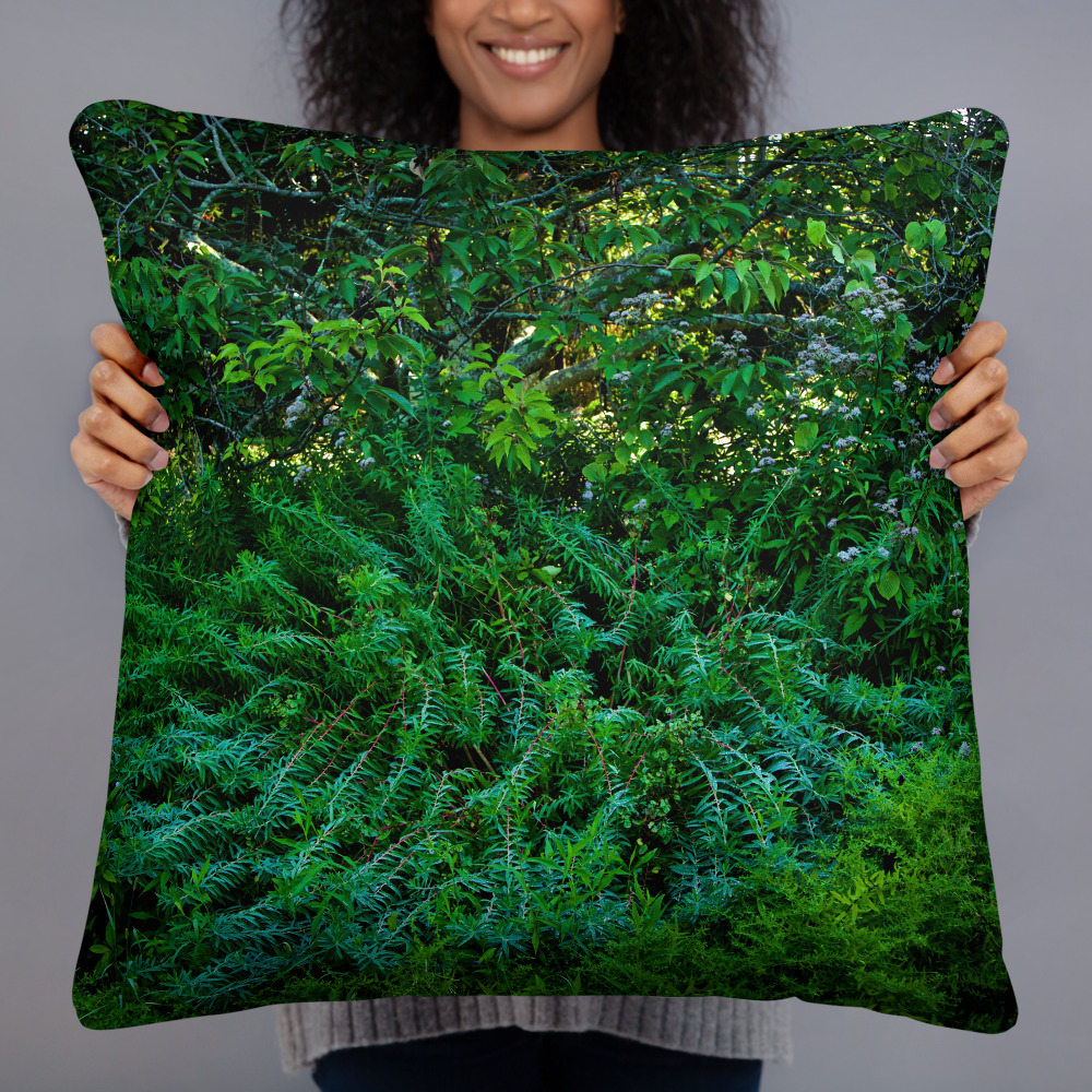 Woman holding a Square pillow with the photograph of lush greenery