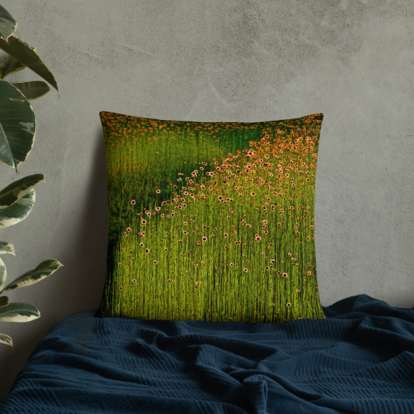 Square pillow with a photograph of a field of orange flowers leaned against a wall