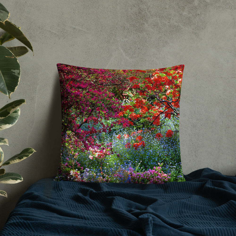 Square pillow with the photograph of a shaded and flowery spot in a park leaned against a wall