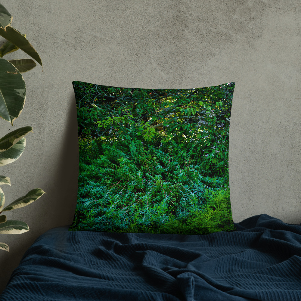 Square pillow with a photograph of lush greenery leaned against a wall