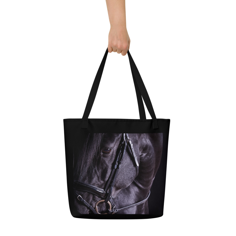 Woman's hand holding a Large black tote bag with the portrait of a black horse on one side