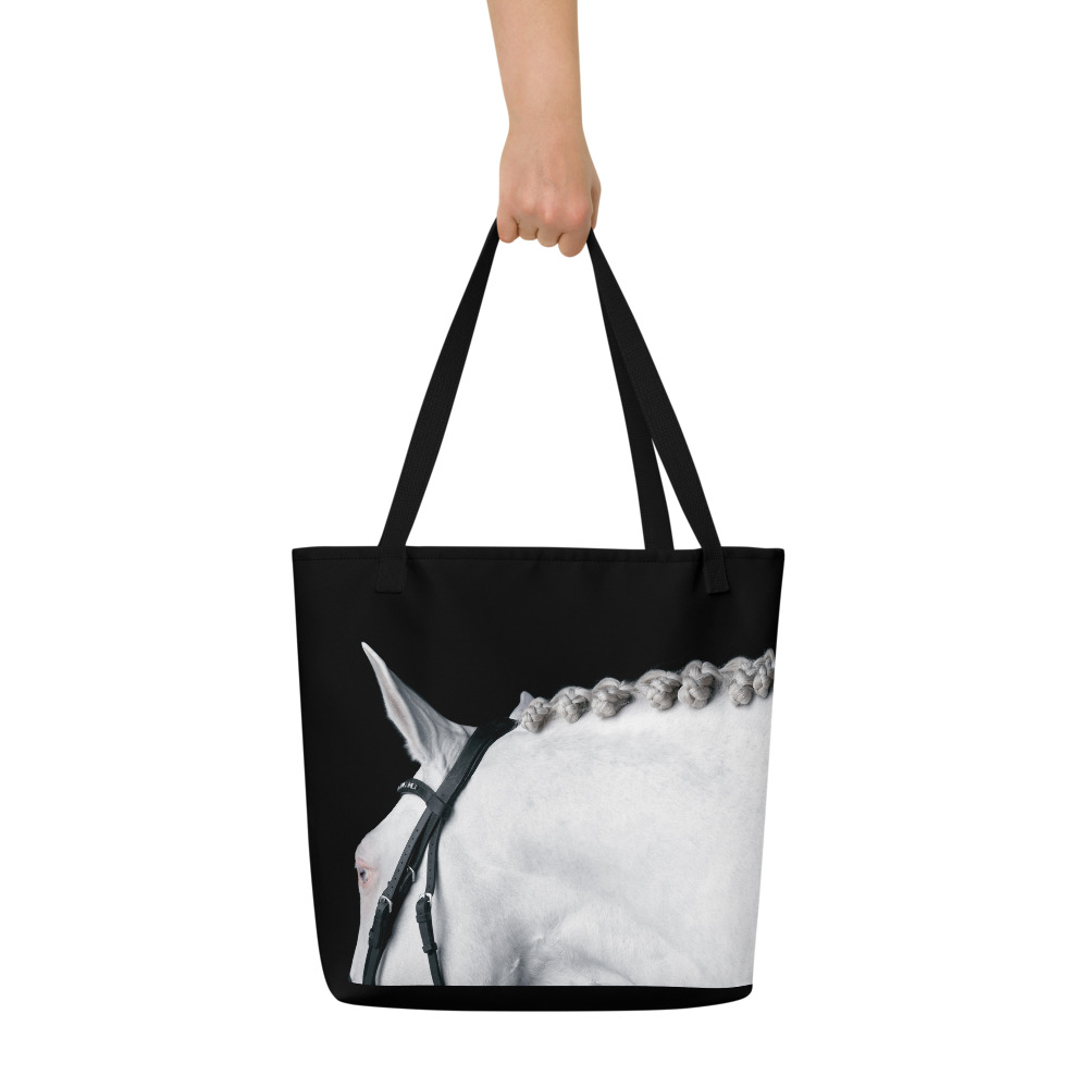 Woman's hand holding a Large black tote bag with the profile of a white horse on one side