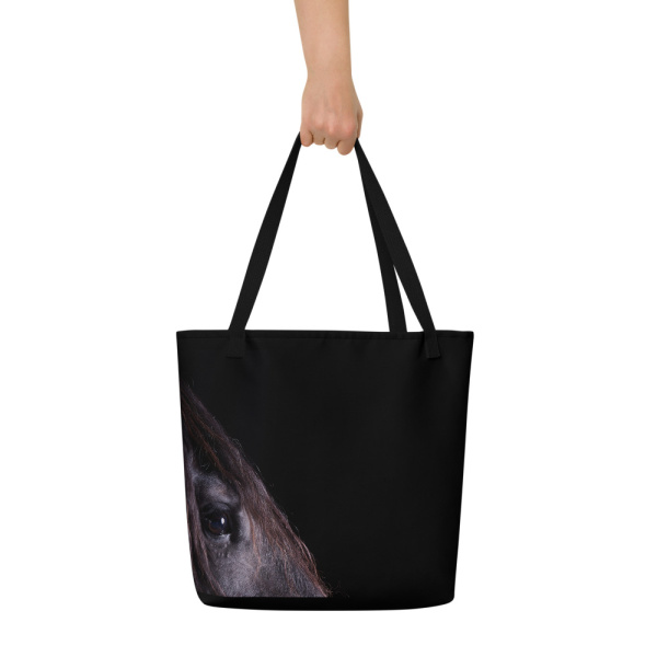 Woman's hand of a Large black tote bag with the profile of a black horse on one side