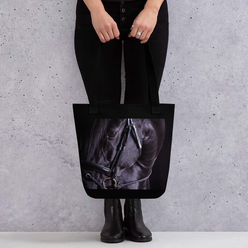 Woman holding a Black tote bag with the portrait of a black horse