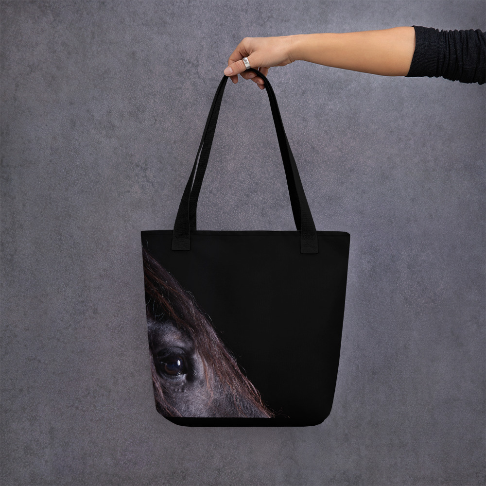 Woman holding a Medium-sized black tote bag with a profile of a black horse on one side