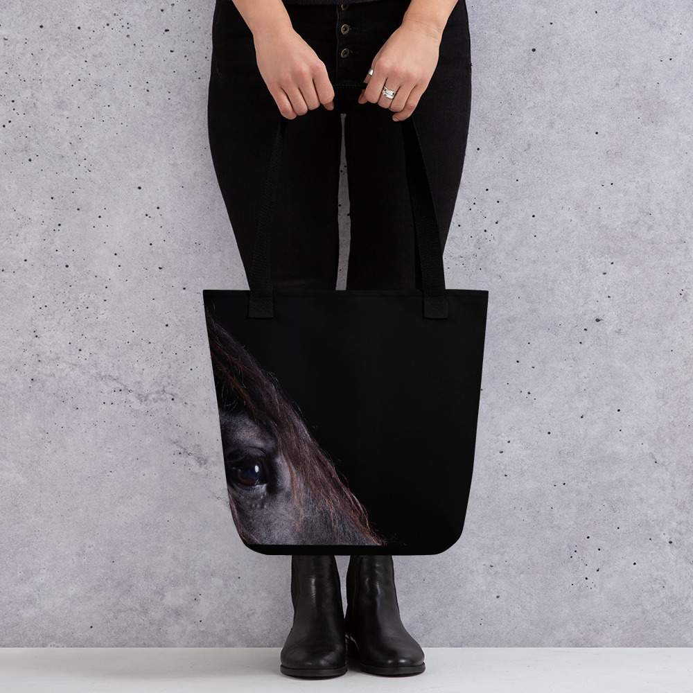 A woman holding a Medium-sized black tote bag with a profile of a black horse on one side