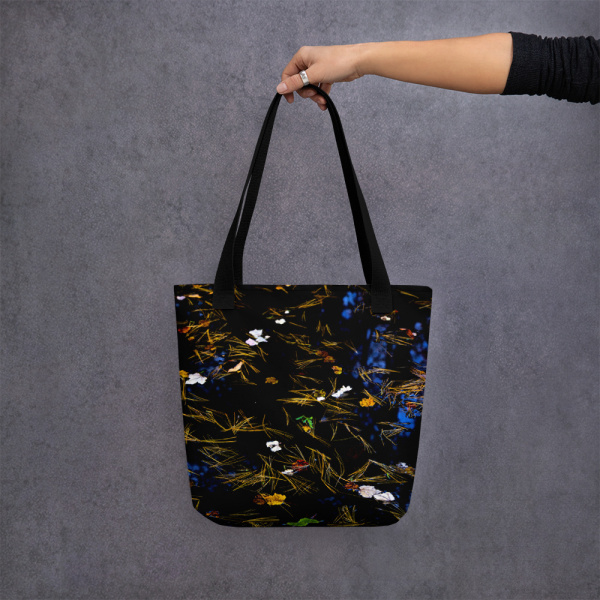 Woman holding a tote bag with an image of a pond covered by fallen petals