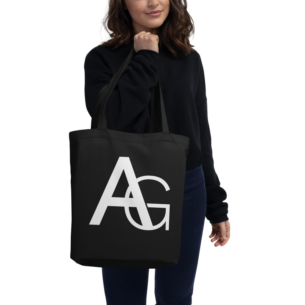 Woman holding a Medium black tote bag with AG initials on front side