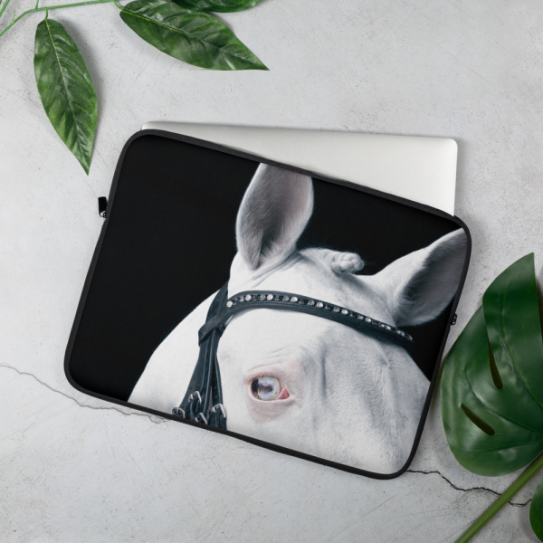 On a table, a Laptop case with a close up of the head and eye of a white horse