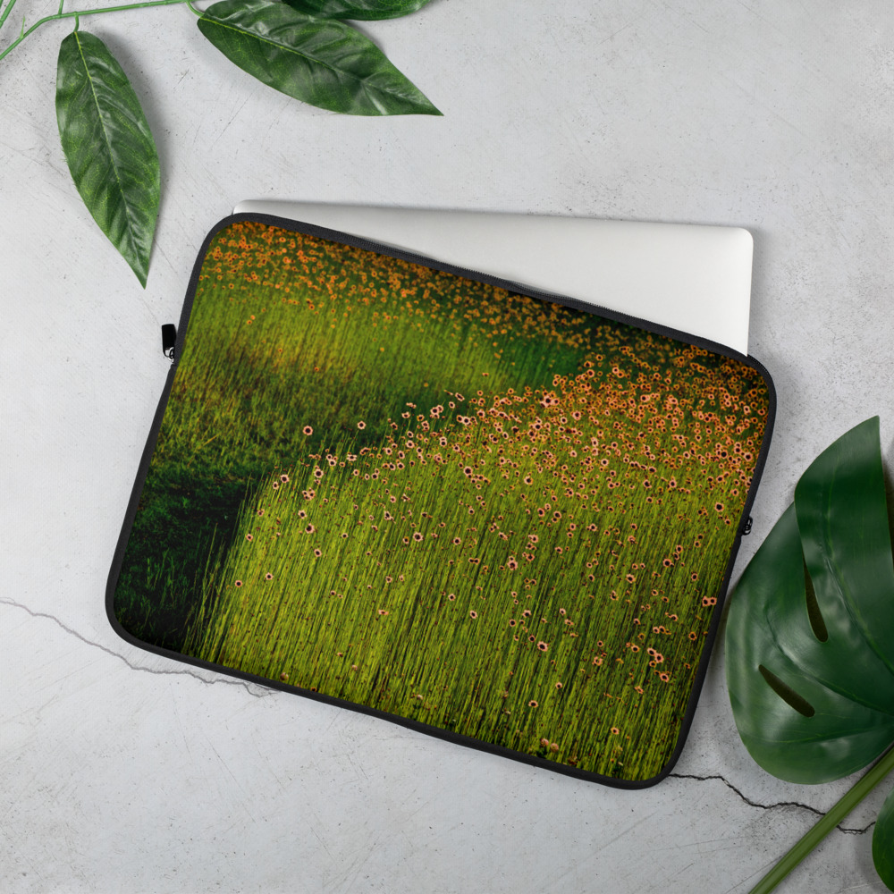 On a table, a Laptop case with the photograph of a field of orange flowers