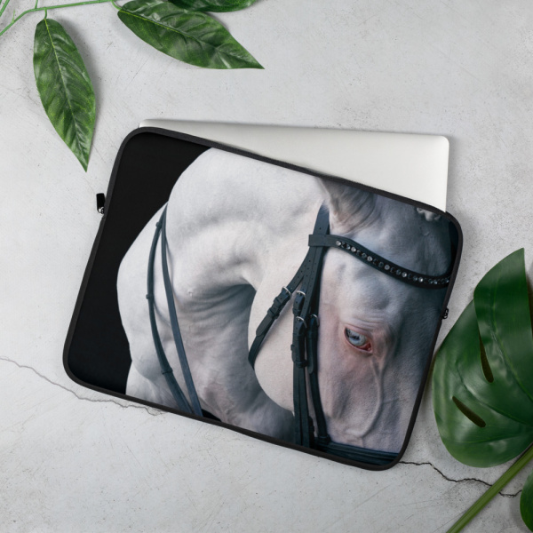 On a table, a Laptop case with a portrait of a white horse