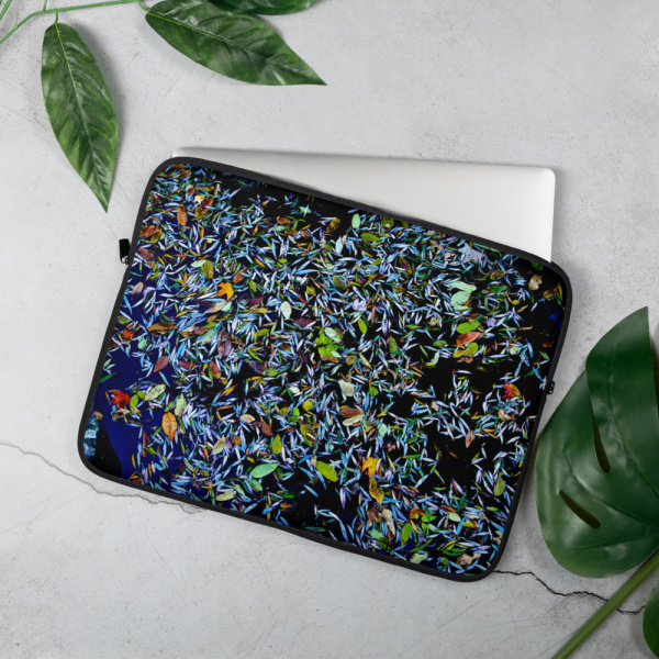 On a table, a Laptop case with the photograph of a pond covered in flower petals (blue tones)