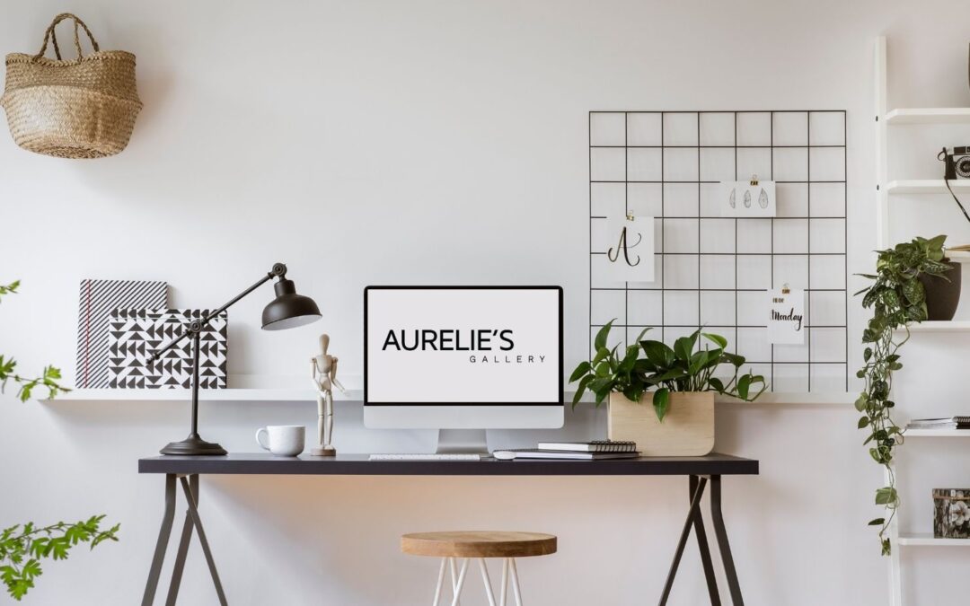 Home office set up with a large monitor on desk showing Aurélie's Gallery logo on its screen